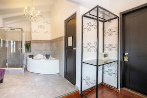 A bathroom with a glass shower enclosure, a white bathtub, and a decorative metal partition.
