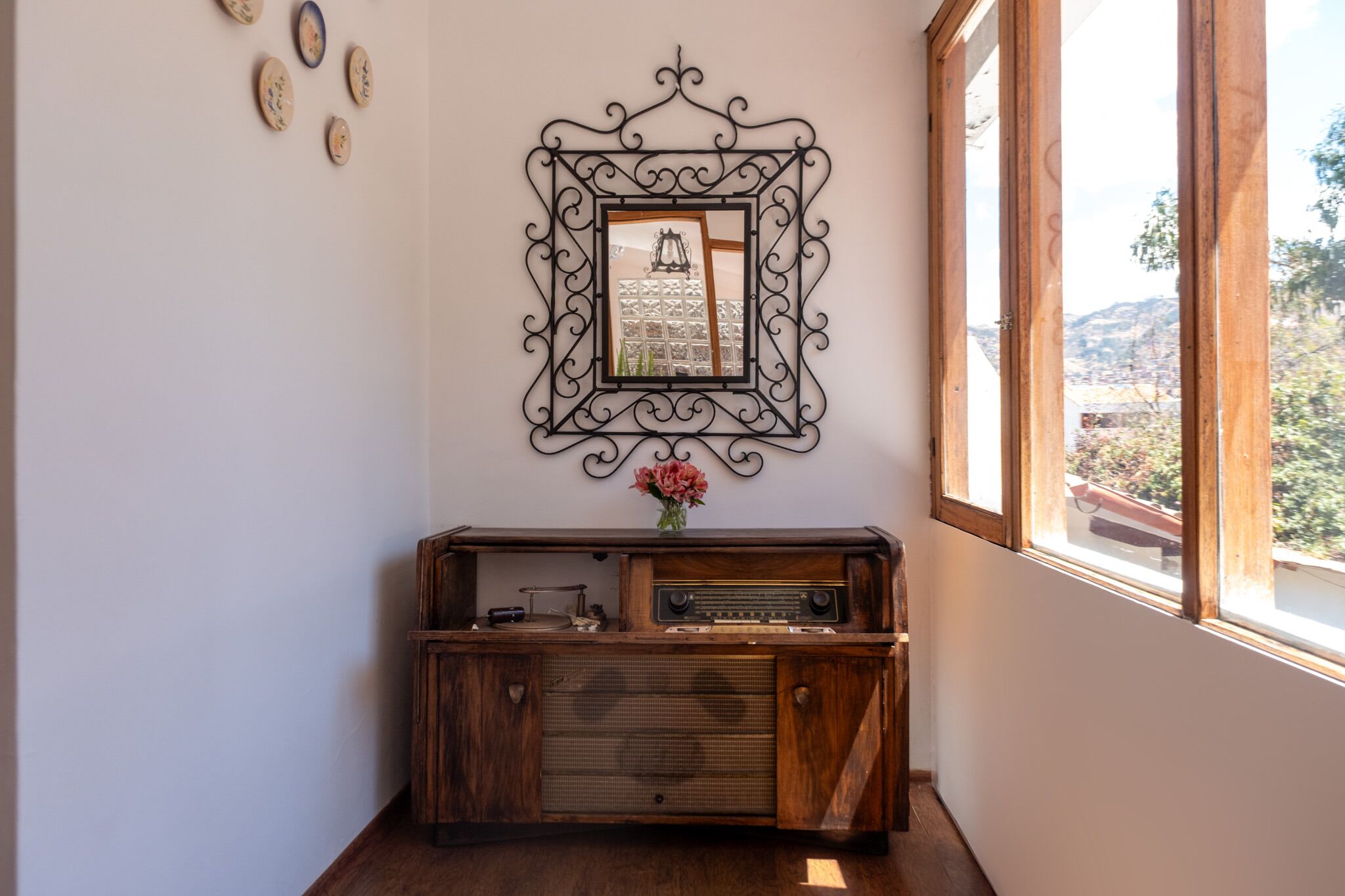 A room with a wooden cabinet, a framed picture, and a window with a view of a mountainous landscape.