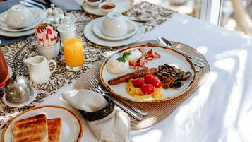 A breakfast table with plates of food, a jug of orange juice, and various condiments.