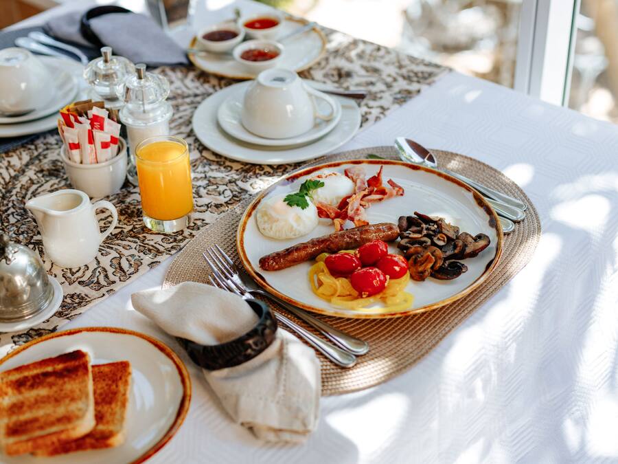 A breakfast table with plates of food, a jug of orange juice, and various condiments.