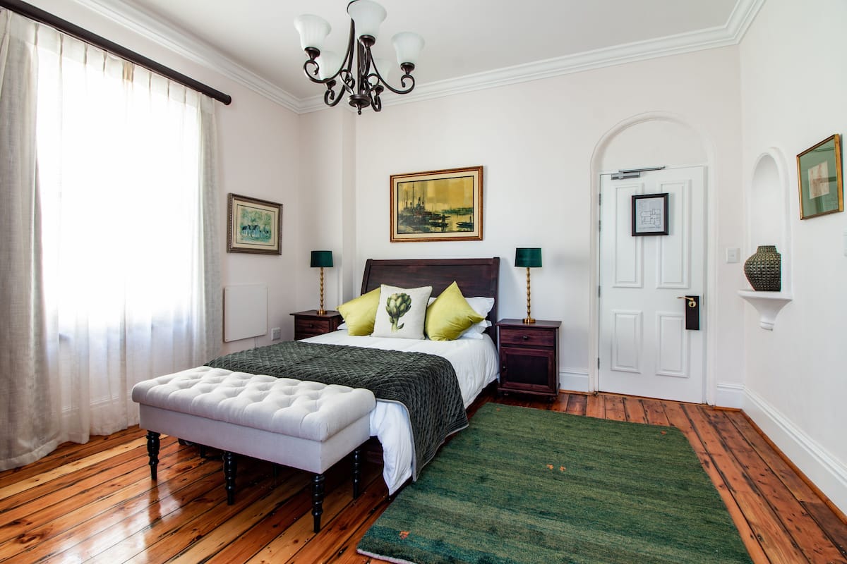 Ein Schlafzimmer mit einem Bett, einer Bank, einer Chandelier und einer Tür.