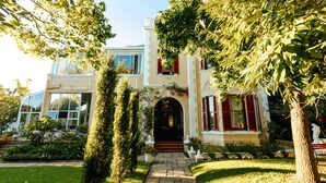 Une maison à deux étages, avec un chemin de pierre menant à l’entrée, entourée d’une végétation bien entretenue et sous un ciel dégagé.
