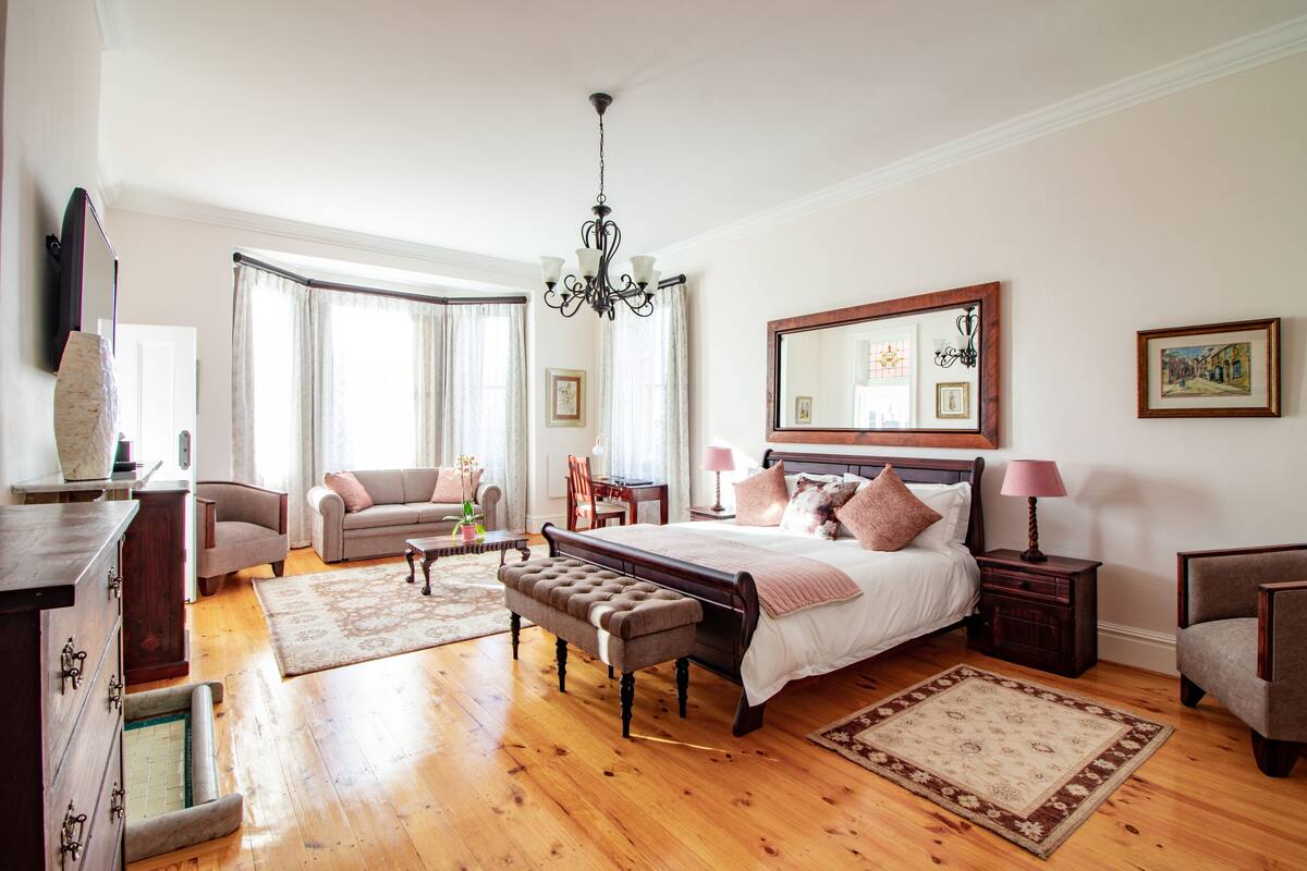 Ein geräumiges Schlafzimmer mit einem großen Bett, einer Sitzecke mit einer Bank, einem Schreibtisch und einem Stuhl.