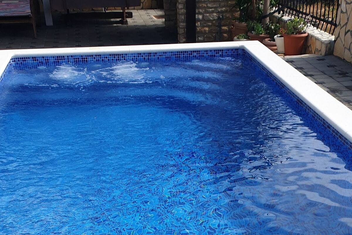 A rectangular swimming pool with blue mosaic tiles.