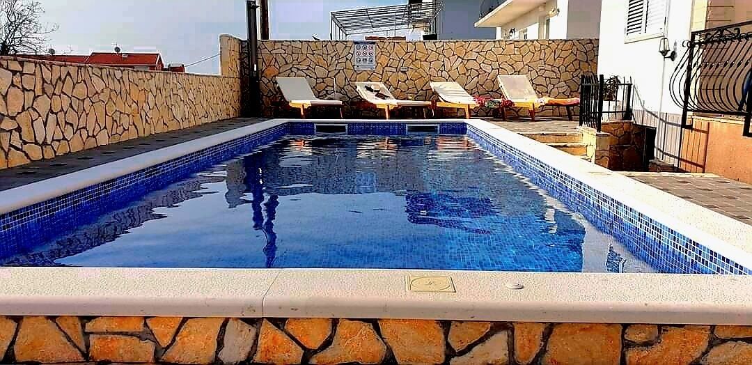 A swimming pool with stone walls and lounge chairs.