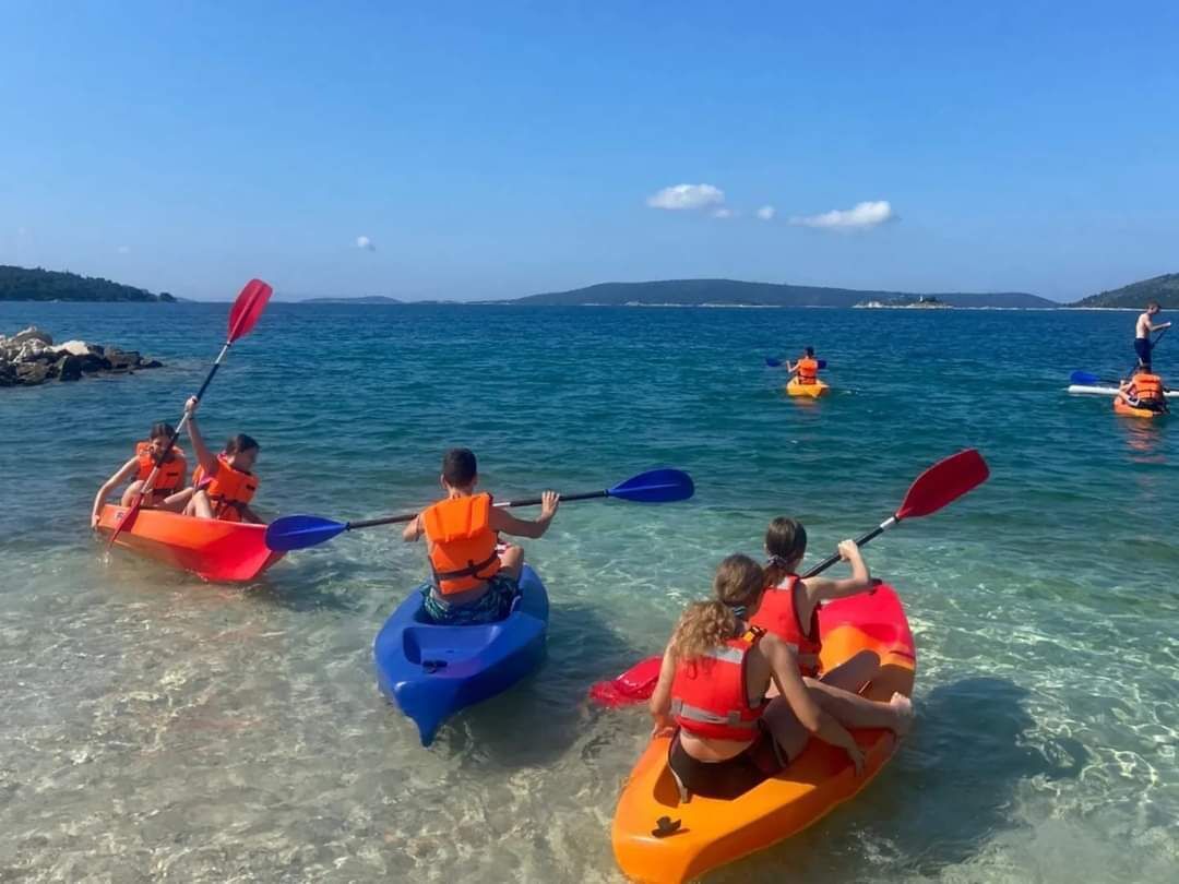 People kayaking in clear water with a distant shoreline.