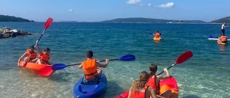 People kayaking in clear water with a distant shoreline.