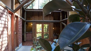 Una cabaña de madera con un camino de piedra, ventanas amplias y plantas de interior.