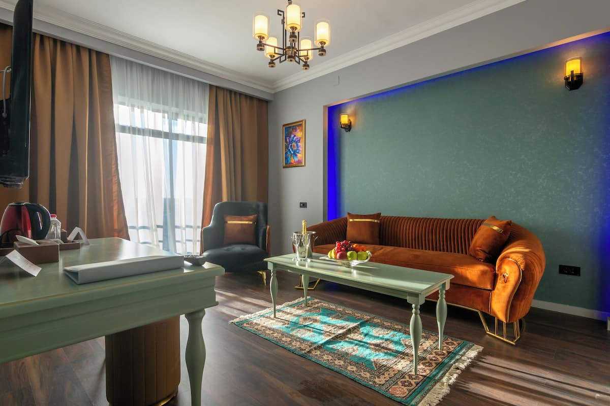 Una sala de estar con sofá, mesa de centro, televisor y ventana con cortinas.