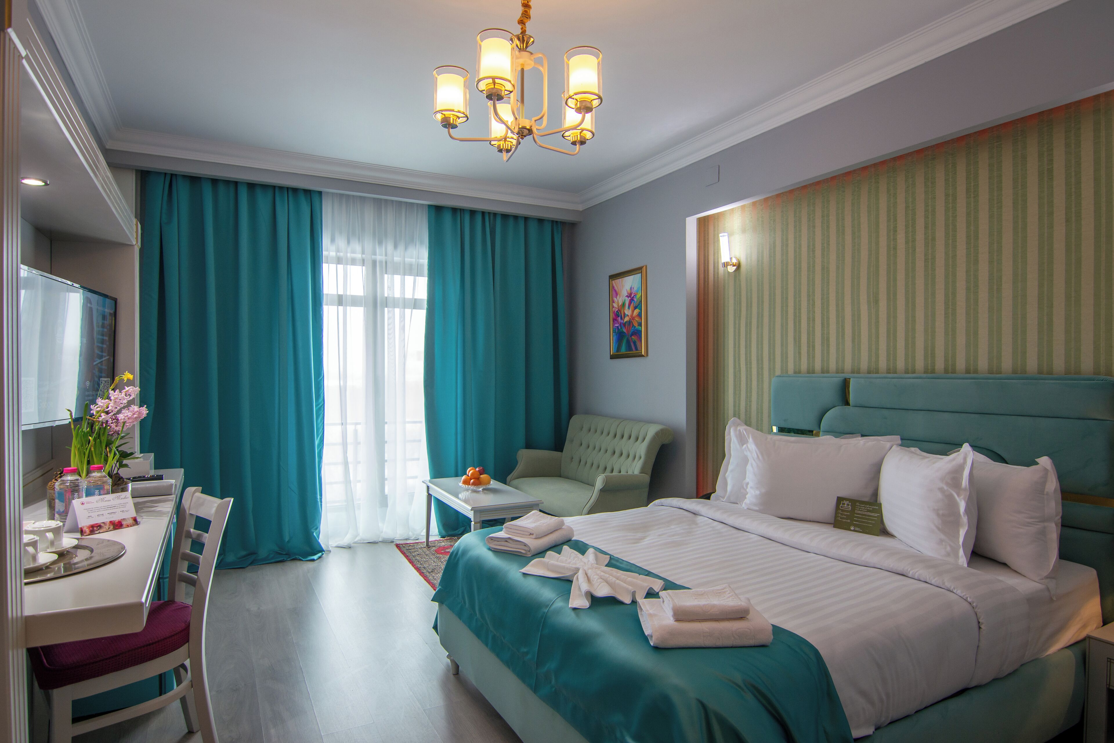 A hotel room with a large bed, a desk with a chair, a television, and a window with curtains.