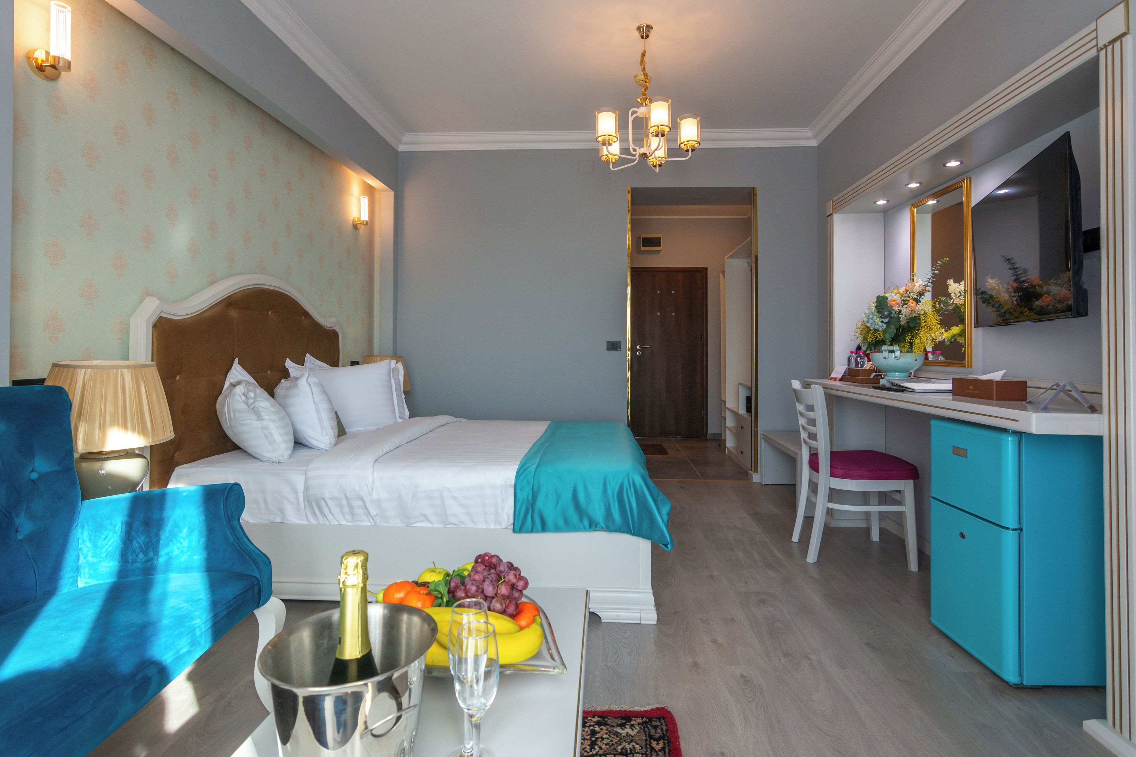 Habitación de hotel con cama, escritorio, silla, minibar y refrigerador.