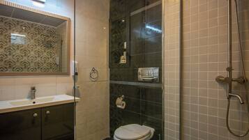 Une salle de bain moderne dotée d’une douche à parois de verre, de toilettes et d’un meuble-lavabo avec un miroir.