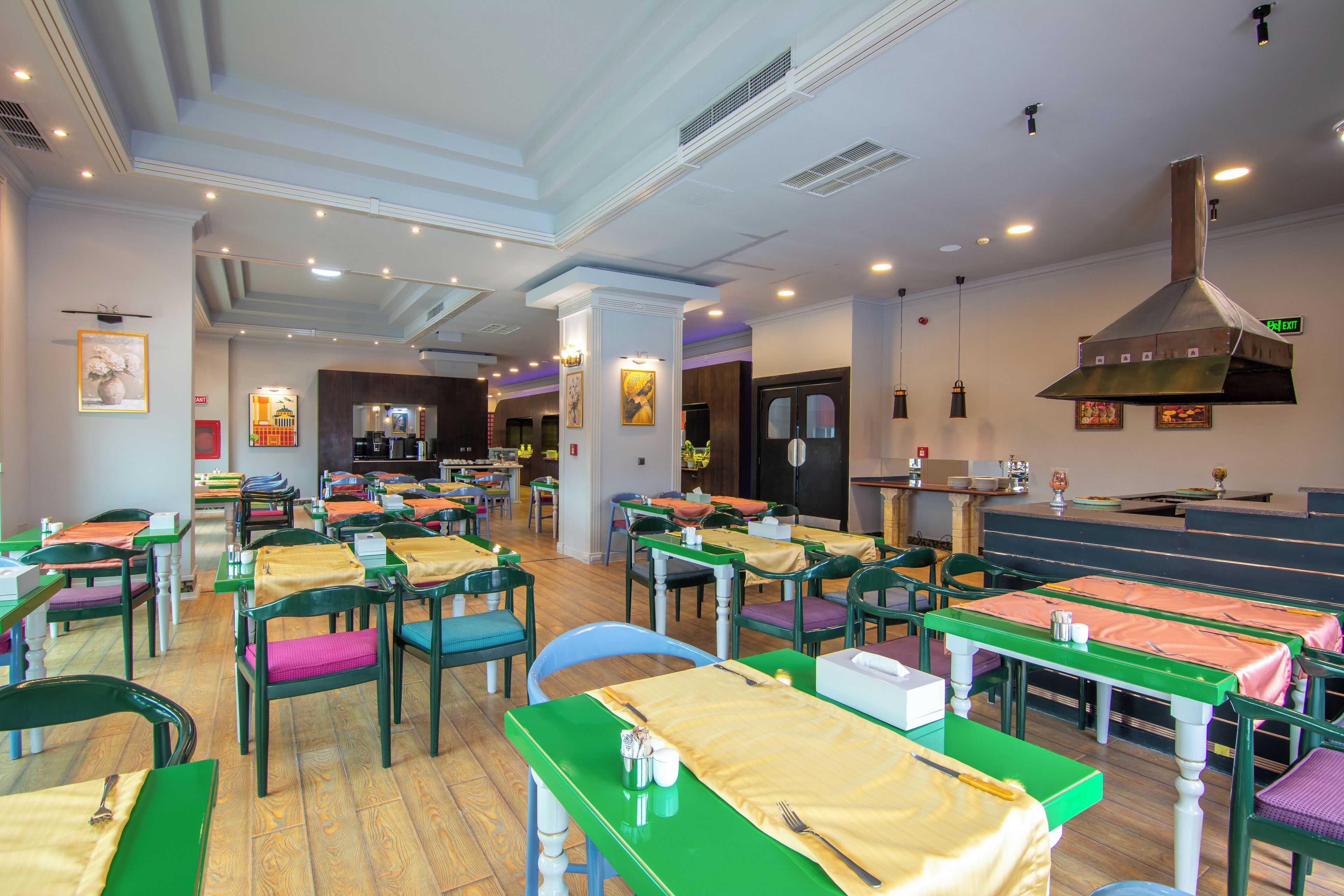 Un restaurante con varias mesas y sillas, un amplio sector de cocina y una barra.