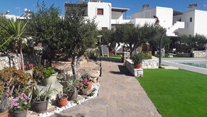 A modern outdoor area with a stone pathway, potted plants, and a swimming pool. - Sunset Studios & Apartments - Adults Only (Paros)