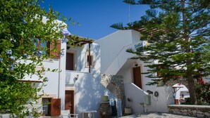 A white building with a stone wall, a wooden door, and a small window. - Sunset Studios & Apartments - Adults Only (Paros)