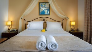A neatly made bed with white linens, two rolled towels, and a single yellow flower. - Sunset Studios & Apartments - Adults Only (Paros)