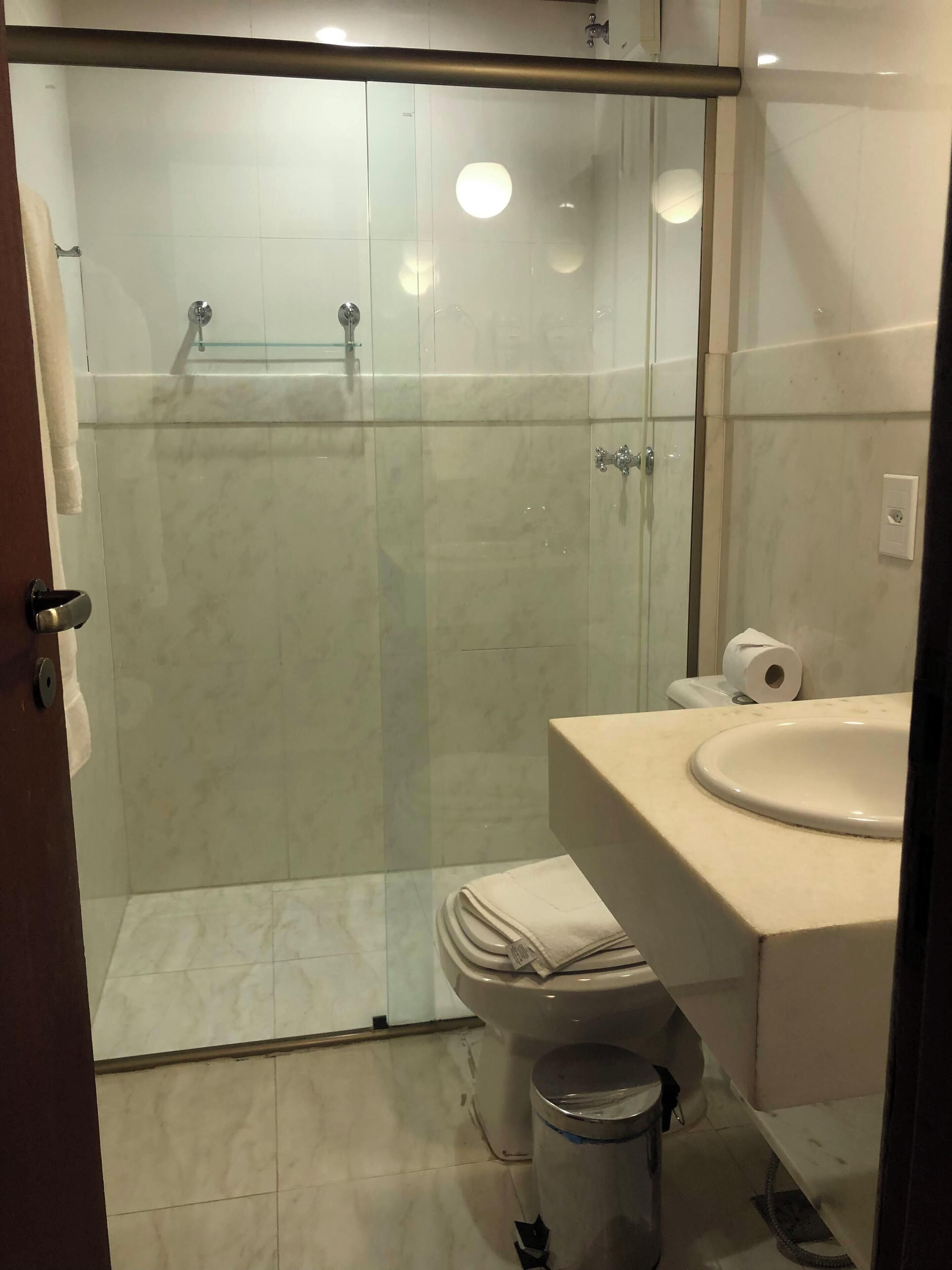 A modern bathroom with a glass-enclosed shower, a toilet, and a sink.