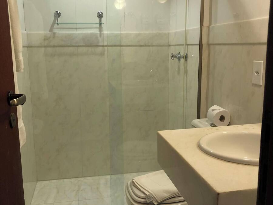 A modern bathroom with a glass-enclosed shower, a toilet, and a sink.