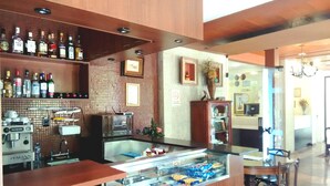 A bar area with a variety of liquor bottles, a coffee machine, and a snack display. - Pousada Minas Gerais (Ouro Preto)