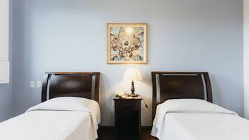 Une chambre d’hôtel avec deux lits simples, une table de chevet avec une lampe et une œuvre d’art encadrée au mur.