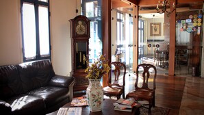A living room with a leather sofa, a wooden coffee table, a vase with flowers, and a grandfather clock. - Pousada Minas Gerais (Ouro Preto)