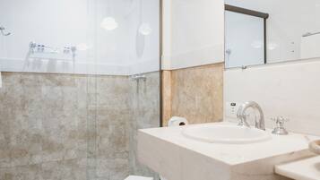 A modern bathroom with a glass shower enclosure, a toilet, and a sink with a mirror above.