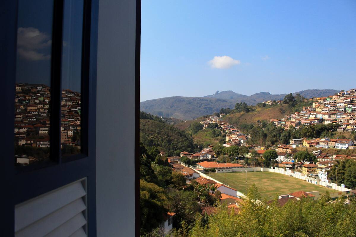 A residential area with houses, a green field, and hills in the background.