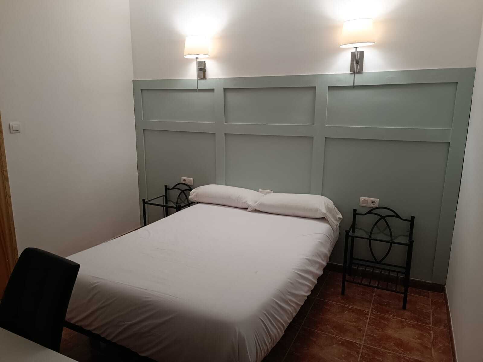 A single bed with a headboard, two bedside tables, and two wall-mounted lamps.