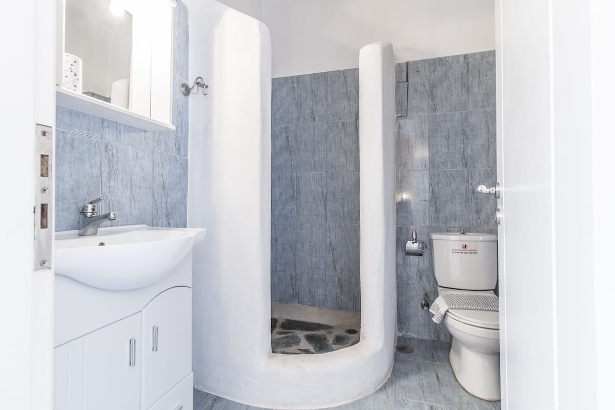 Ein Badezimmer mit weißem Waschbecken, Toilette und Dusche mit Marmorwand.