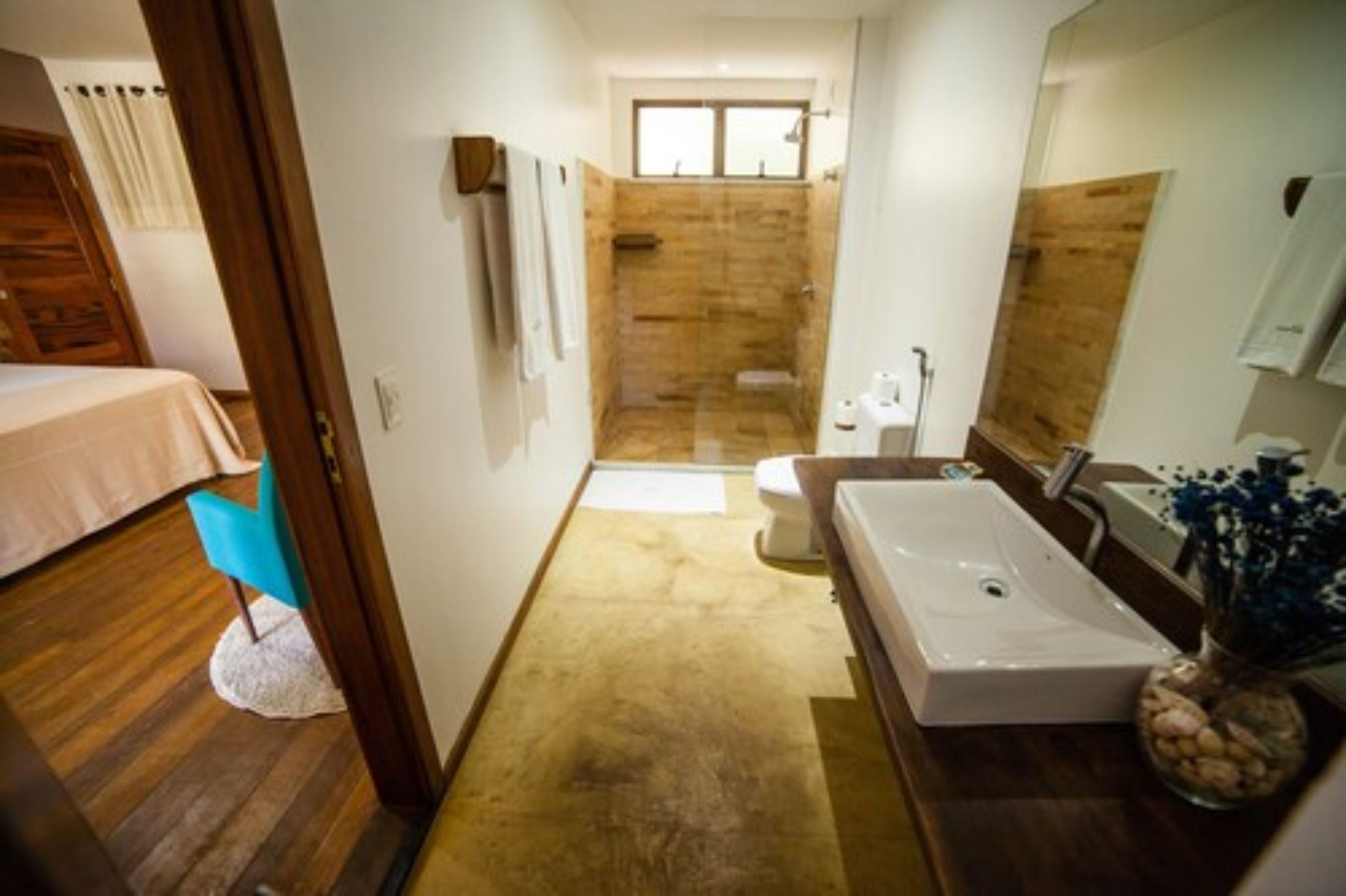 A narrow bathroom with a shower, toilet, and sink.