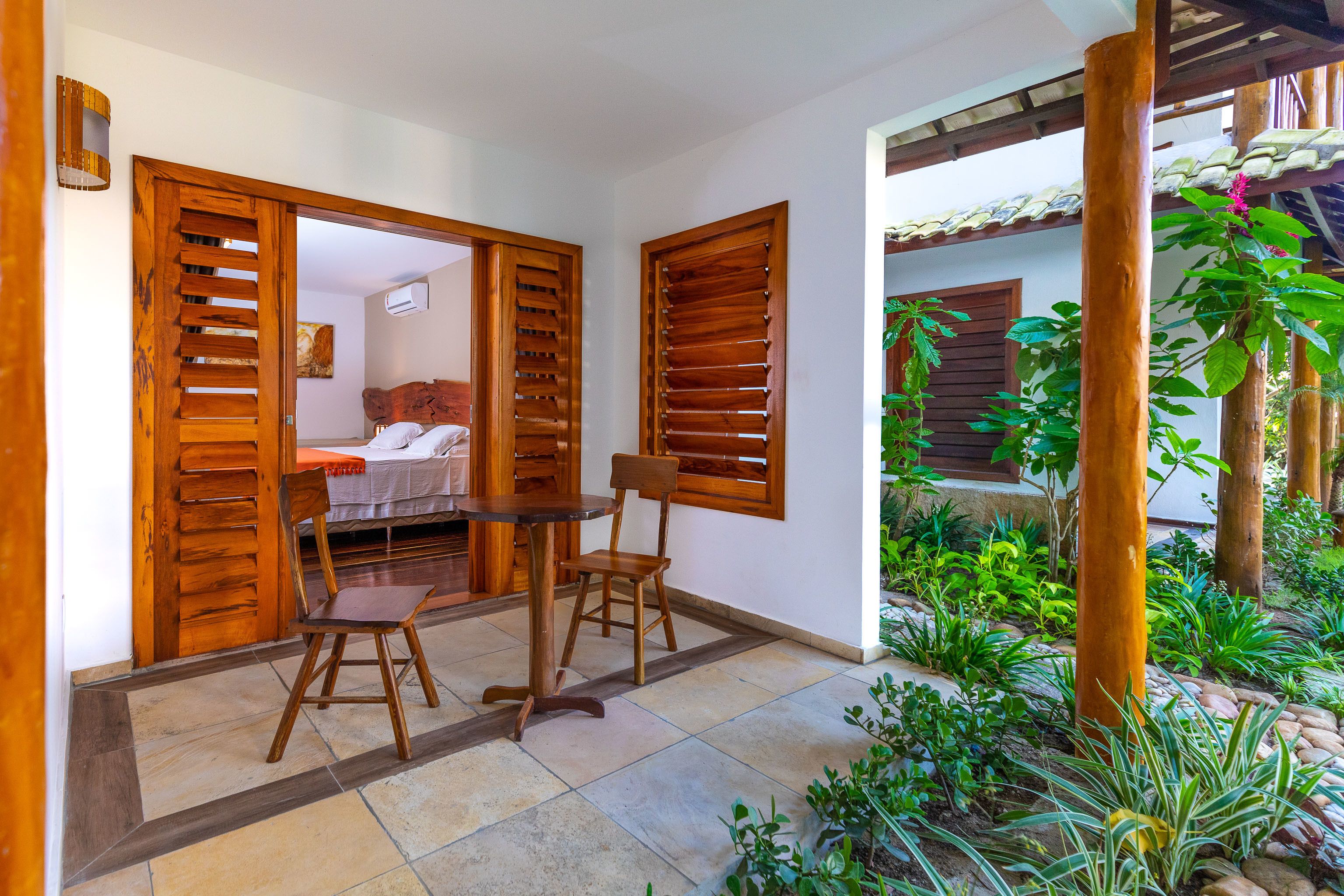 Una habitación con una cama, contraventanas de madera, una mesa y sillas.