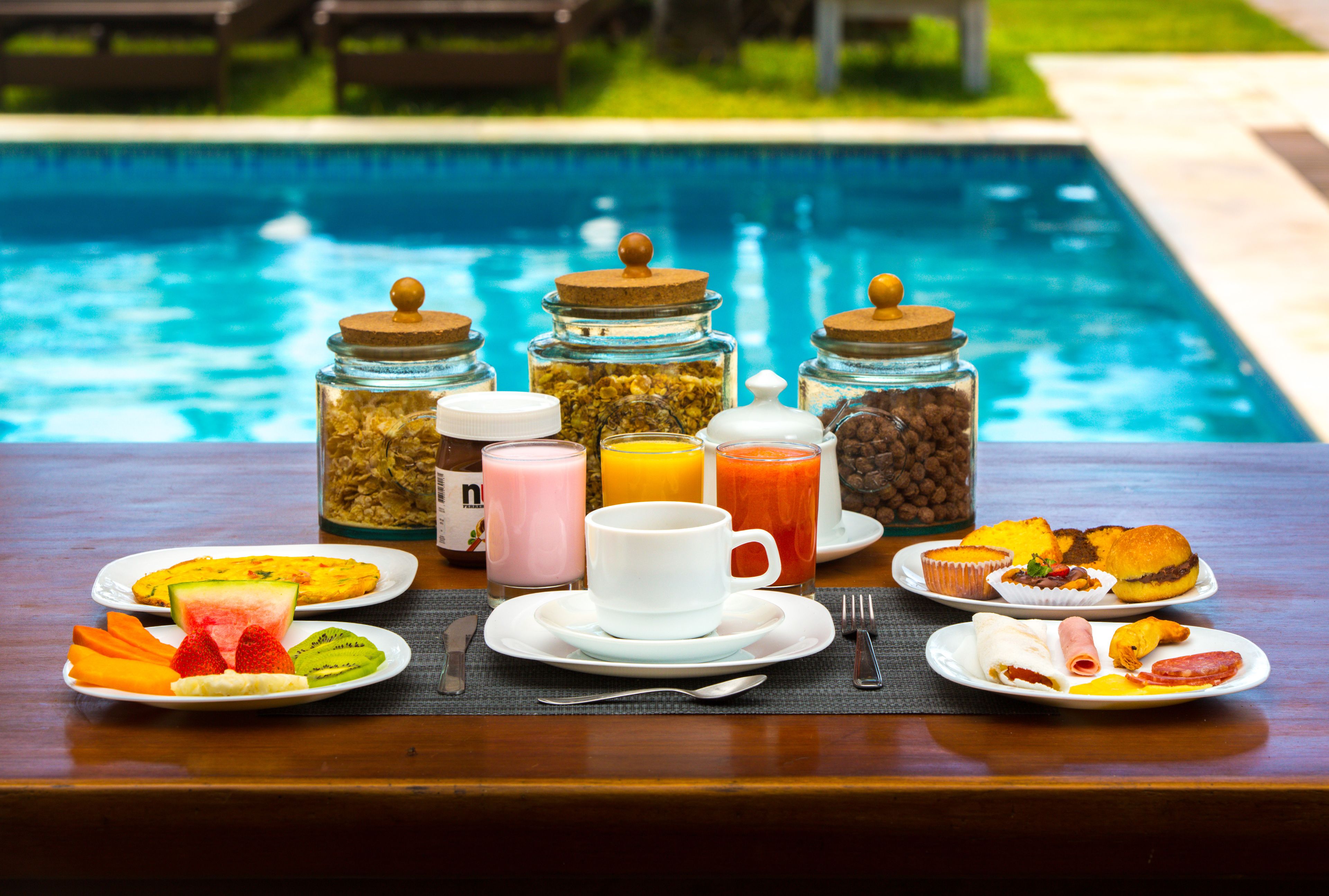 Un buffet de petit-déjeuner proposant divers plats et boissons, servi au bord de la piscine.