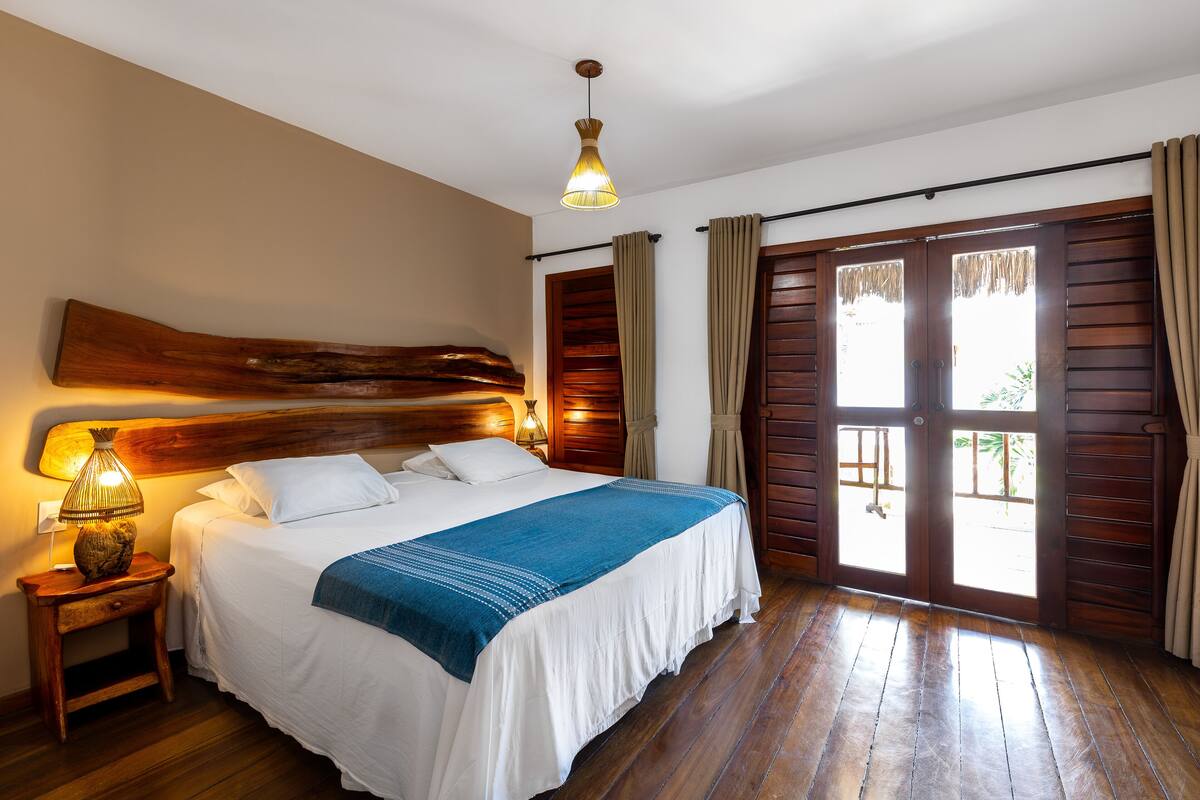 A neatly made bed with a blue throw, wooden headboard, and a nightstand with a lamp.