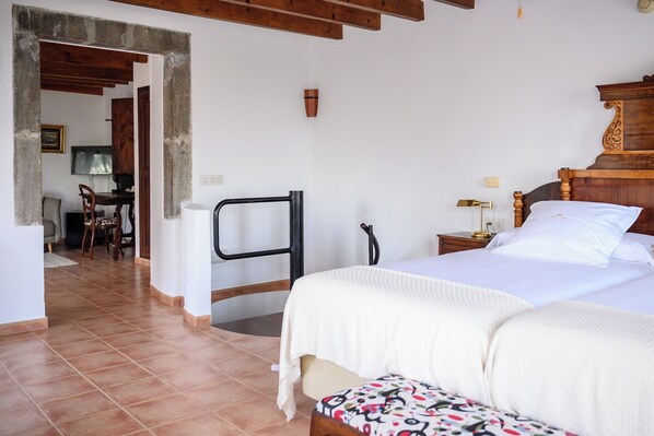 A bedroom with a bed, bedside table, and a chair. There is a desk and chair in the adjacent room. - Muleta de Ca S'Hereu Agroturismo (Sóller)