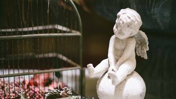 A statue of a figure sitting on a ball next to a birdcage with flowers.