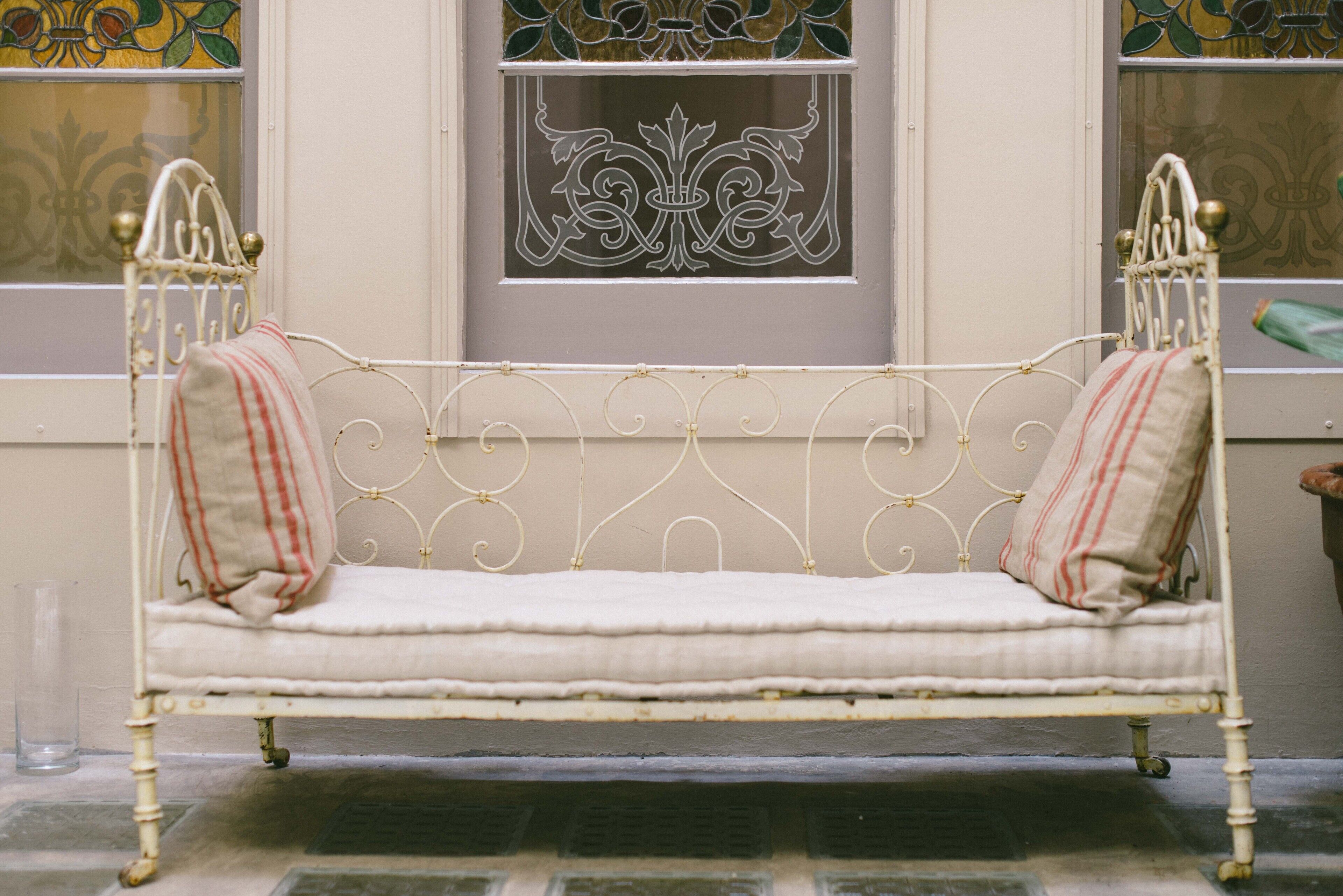 Un banco de metal blanco con almohadas a rayas rojas y blancas.