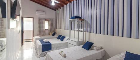 A hotel room with three single beds, a ceiling fan, and a striped wall.