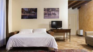 Una habitación de hotel con cama, televisión, escritorio y dos cuadros en la pared.