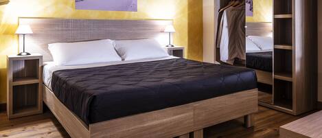 A neatly made bed with a wooden frame, two bedside tables, and a wardrobe with a mirror.