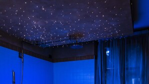 Un bain à remous avec un plafond étoilé, des murs bleus et un banc en bois.