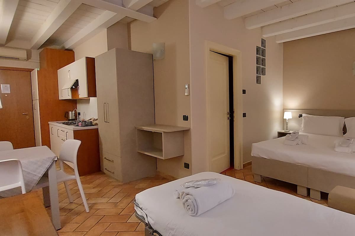 Habitación de hotel con cama, mesitas de noche, escritorio, silla, kitchenette y baño.