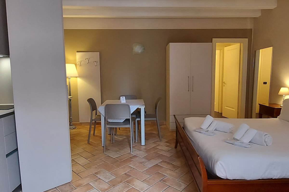 Habitación de hotel con cama, escritorio, silla, armario y kitchenette.