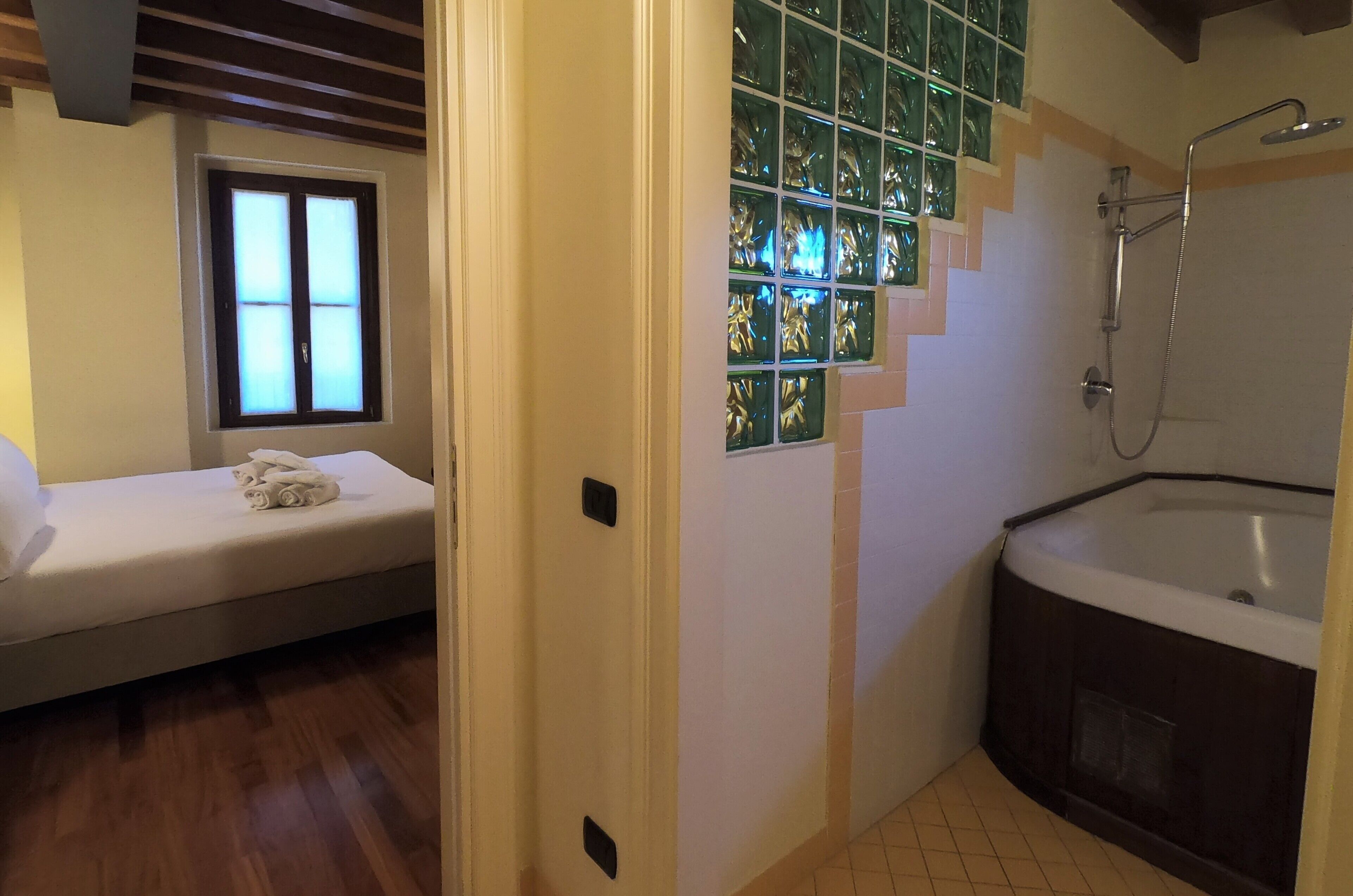 A room with a bed, a window, a shower, and a bathtub.