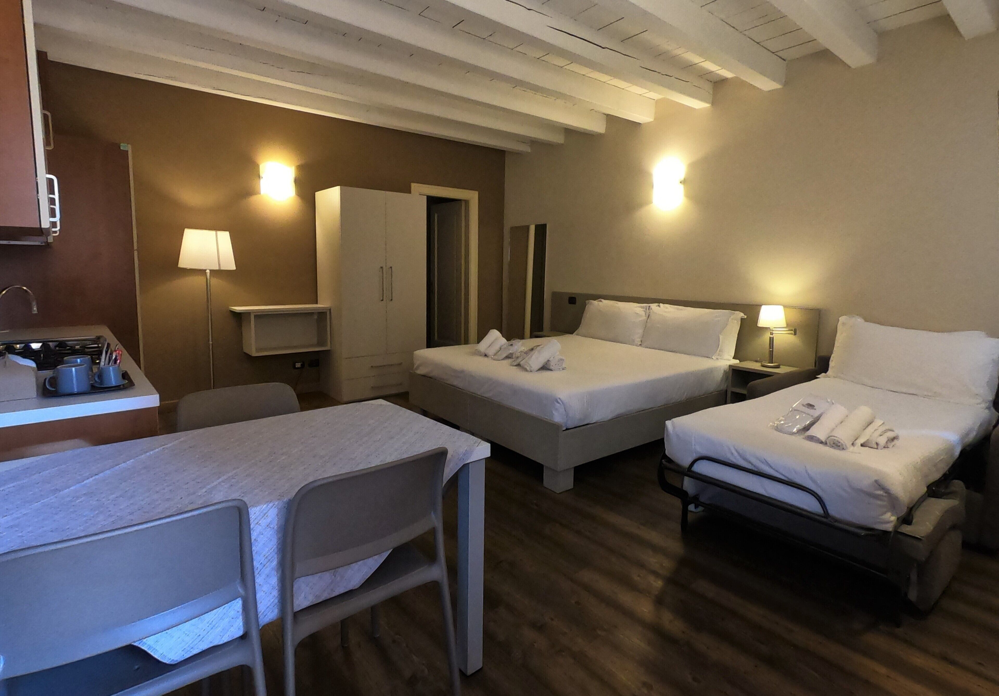 Een hotelkamer met twee bedden, een bureau met stoel, een lamp en een kledingkast.