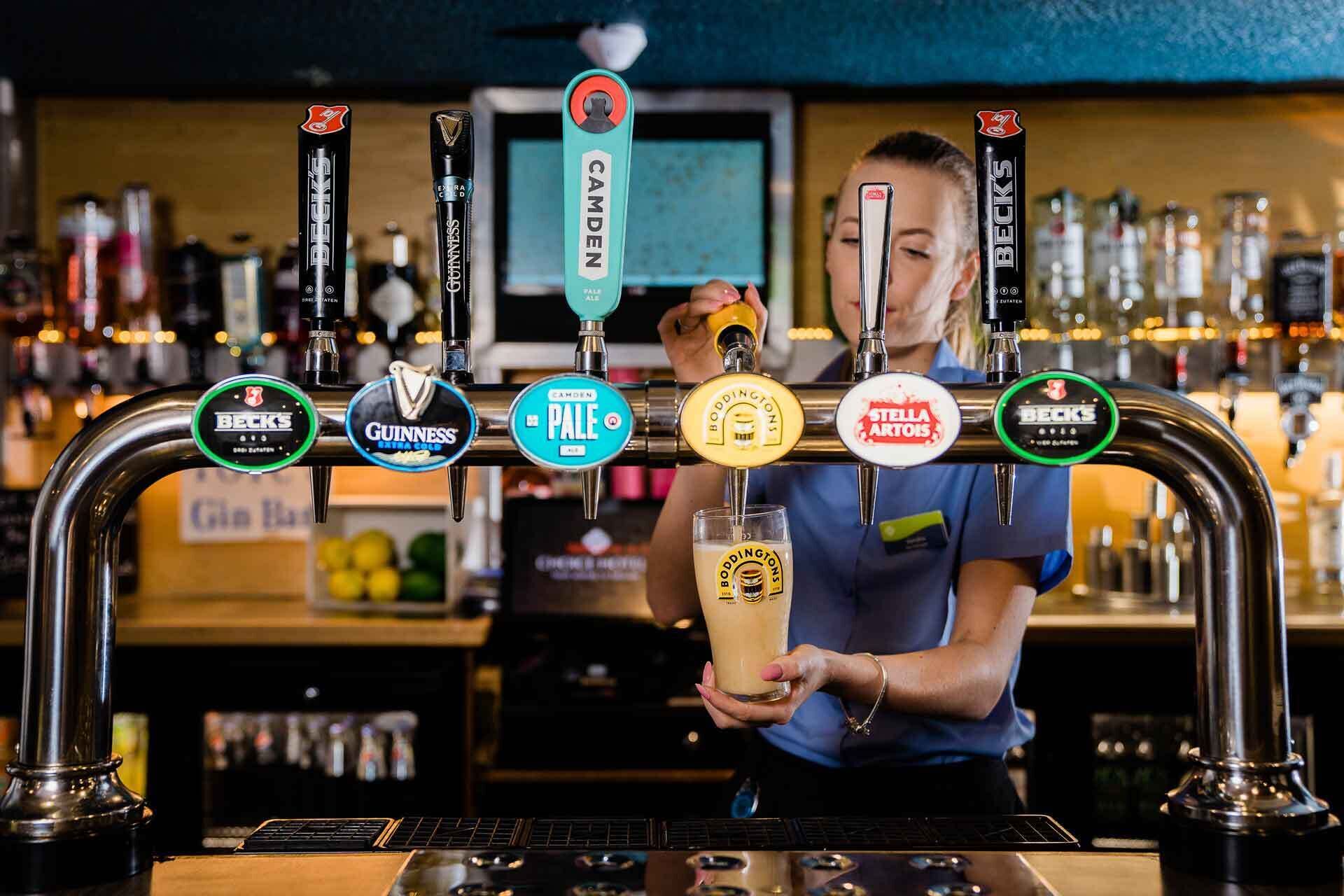 Un bar con múltiples grifos de cerveza, incluyendo marcas como Beck's, Guinness y Boddingtons.
