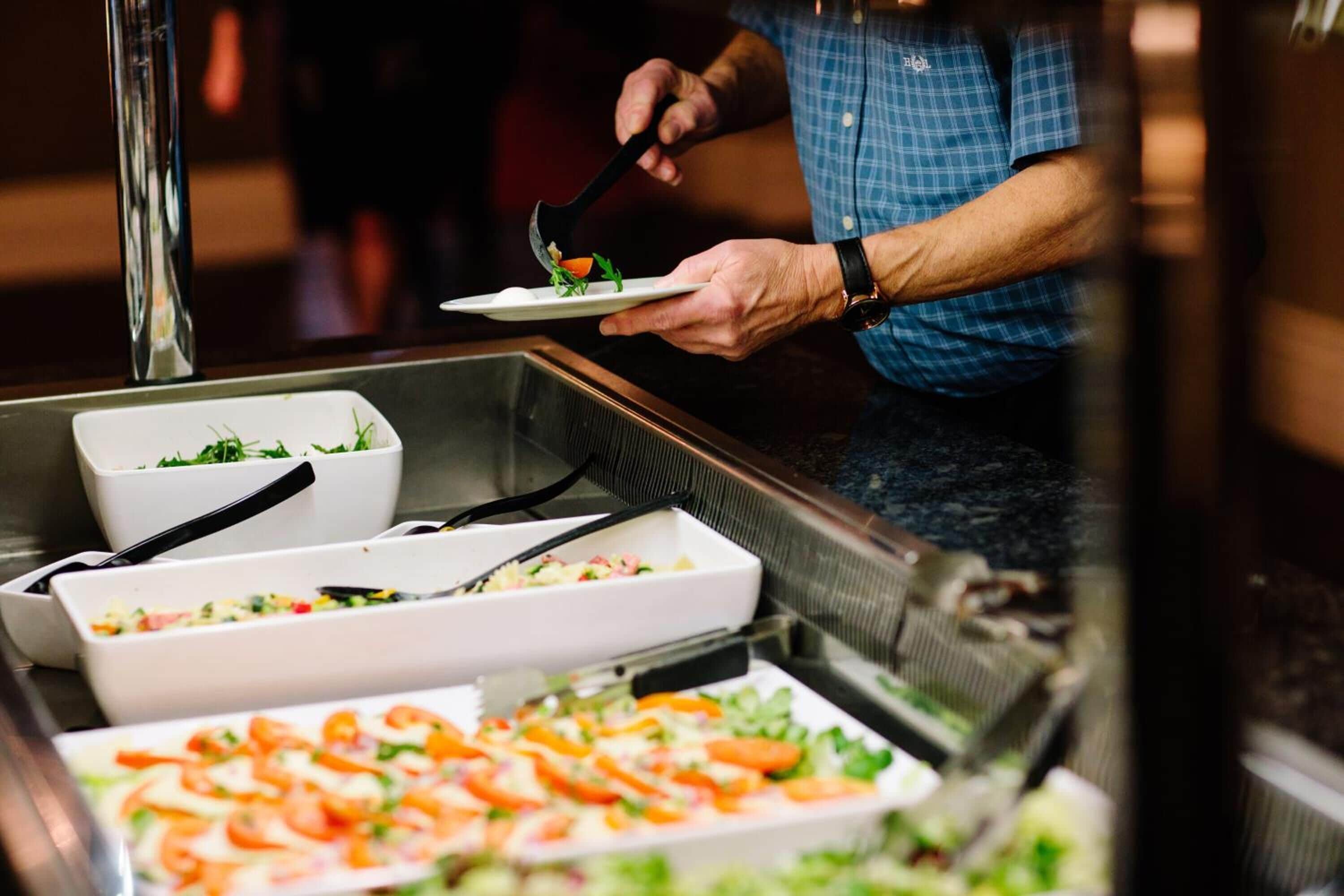 Een buffetopstelling met diverse gerechten, waaronder salades en pizza.