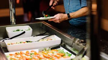 Een buffetopstelling met diverse gerechten, waaronder salades en pizza.