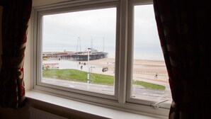A window with a view of a beach and a pier.