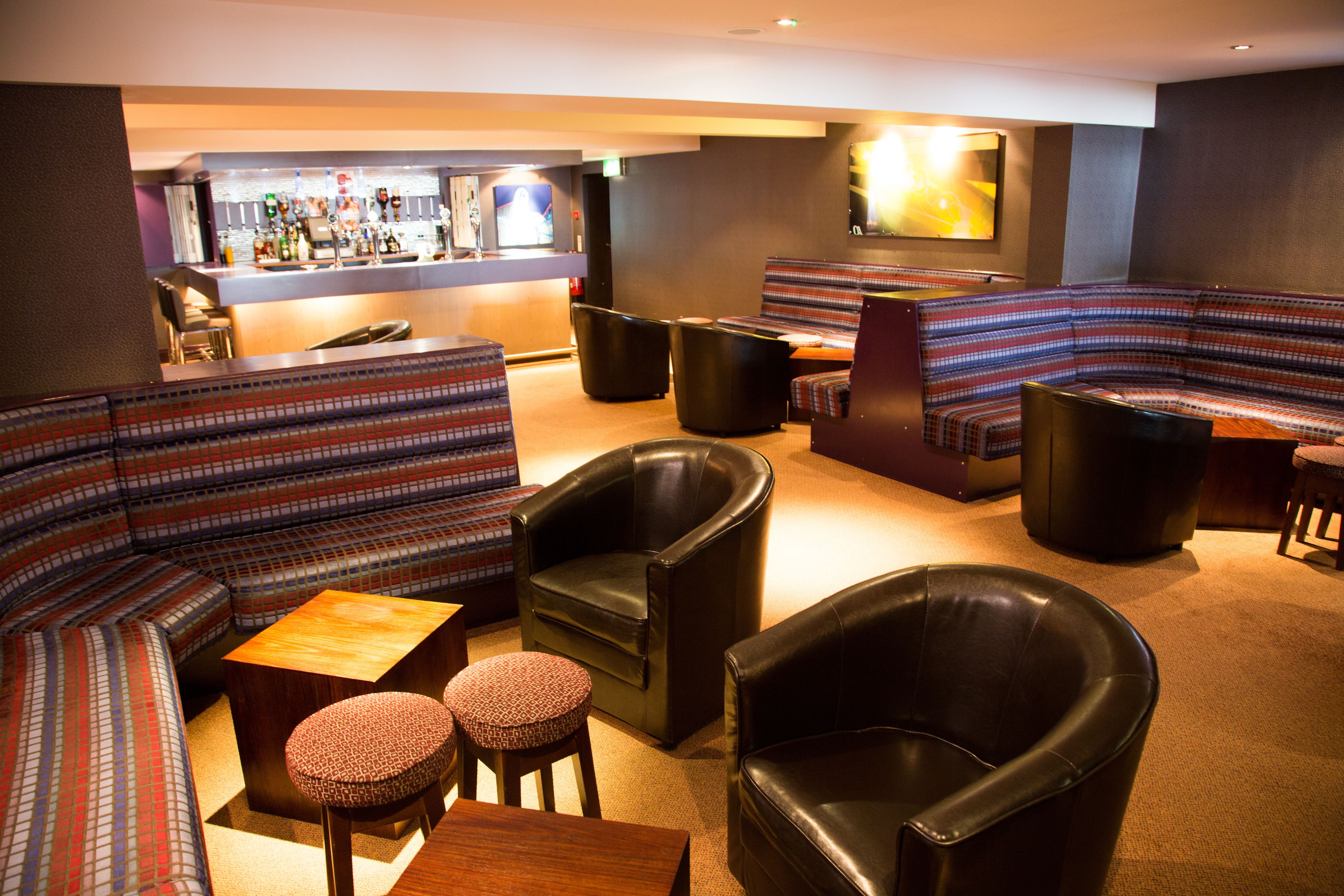 A lounge area with a bar, sofas, and leather chairs.