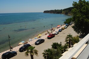 Une plage avec des voitures garées et des parasols, un ciel dégagé et une mer calme.